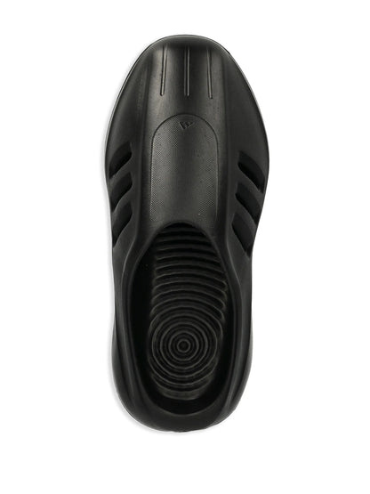 Black slip-on shoe with textured sole on a white background