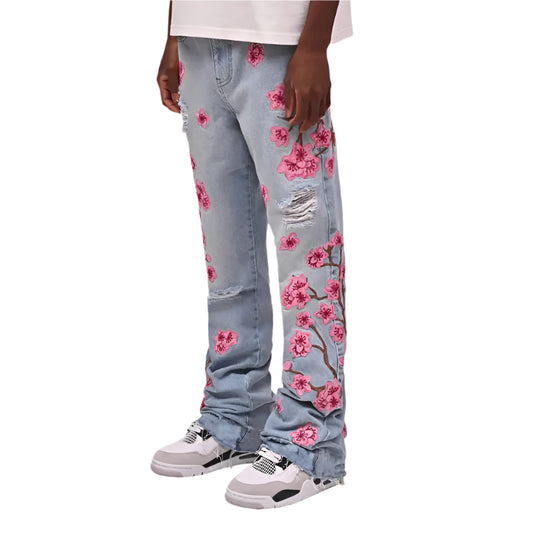 Light blue jeans with pink floral patterns worn by a person on a white background